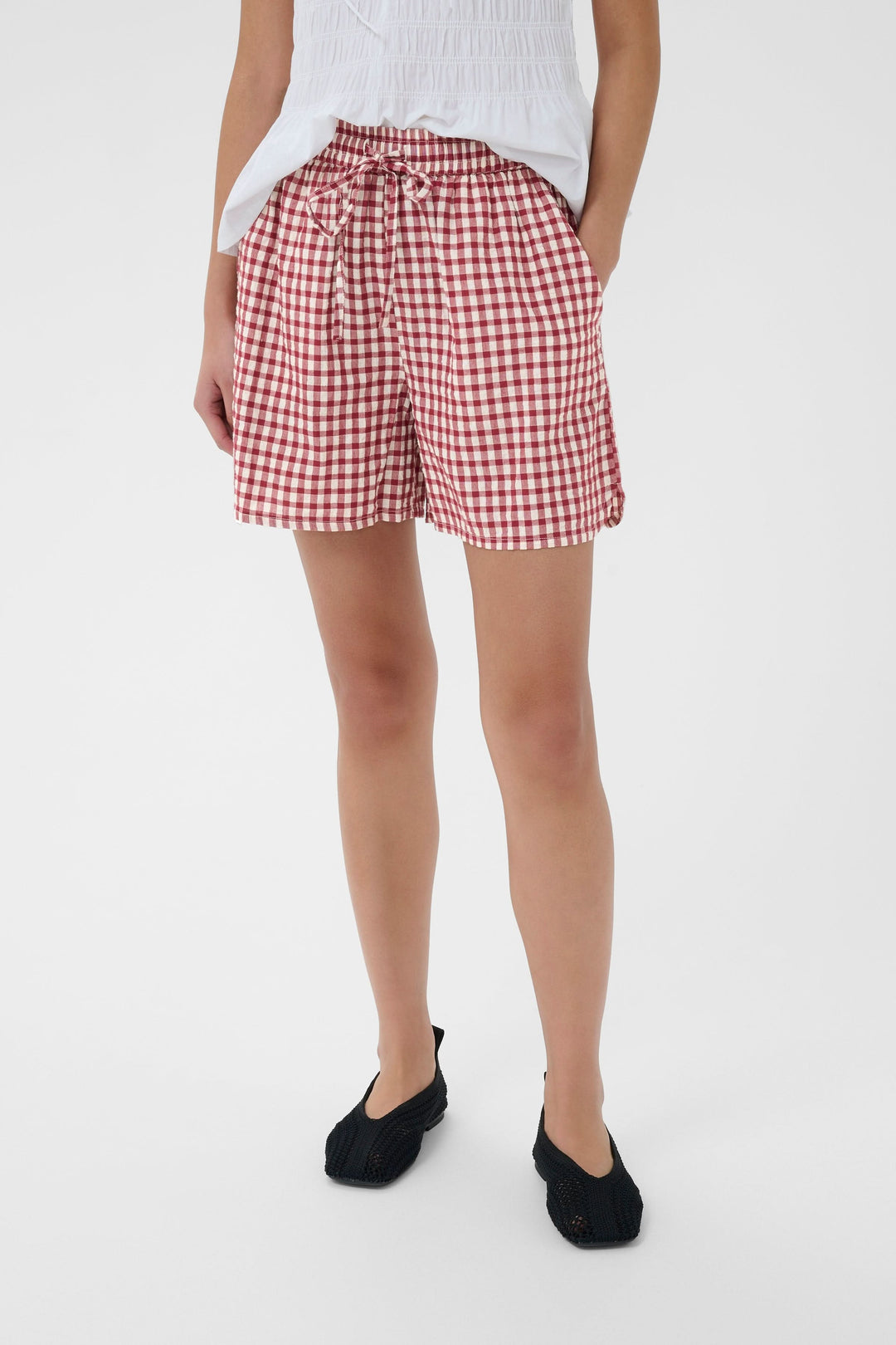 Femme portant le Bermuda Bigi à carreaux taille élastiquée, léger et confortable, avec cordon de serrage et poches latérales.