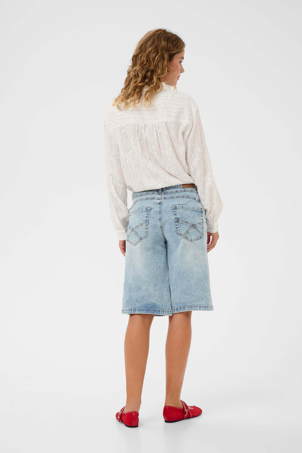 Femme portant le Bermuda Joani en denim, coupe droite, longueur genou, vue de dos, mode estivale décontractée et soignée.