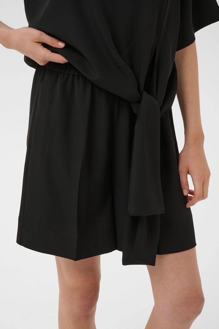 Femme portant un Bermuda Varina fluide taille élastique ceinturé noir avec une ceinture nouée.