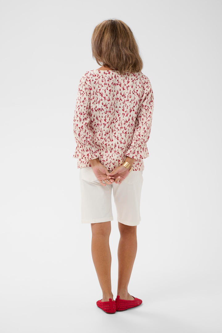 Femme portant une Blouse Bellis à motif délicat avec manches trois-quarts et encolure en V, vue de dos.