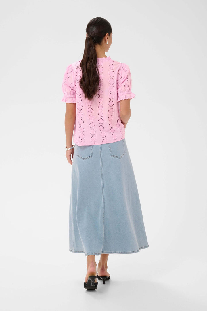 Blouse Dona brodée à manches courtes avec encolure volantée, vue de dos, portée avec une jupe en jean.