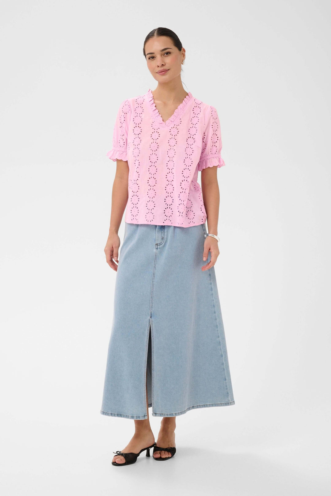 Femme portant la Blouse Dona brodée à manches courtes avec encolure volantée, associée à une jupe longue en jean.