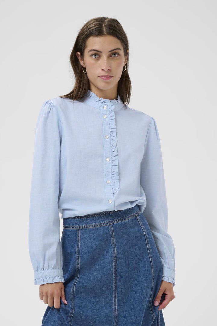 Blouse Glessia romantique avec volants subtils, coupe fluide et col montant, idéale avec un jean ou une jupe.