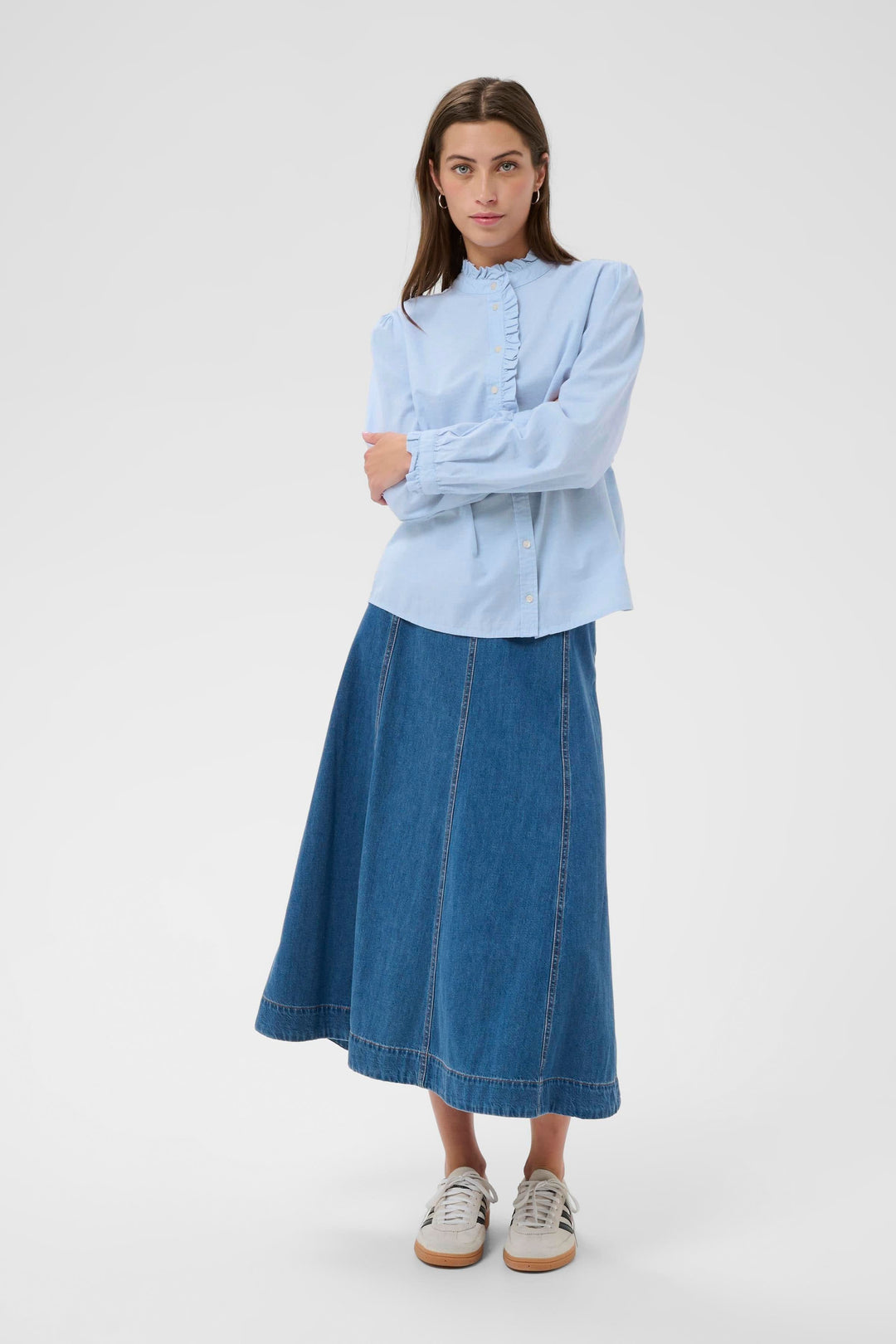 Blouse Glessia romantique avec volants subtils et coupe fluide, assortie à une jupe en denim pour un style raffiné.