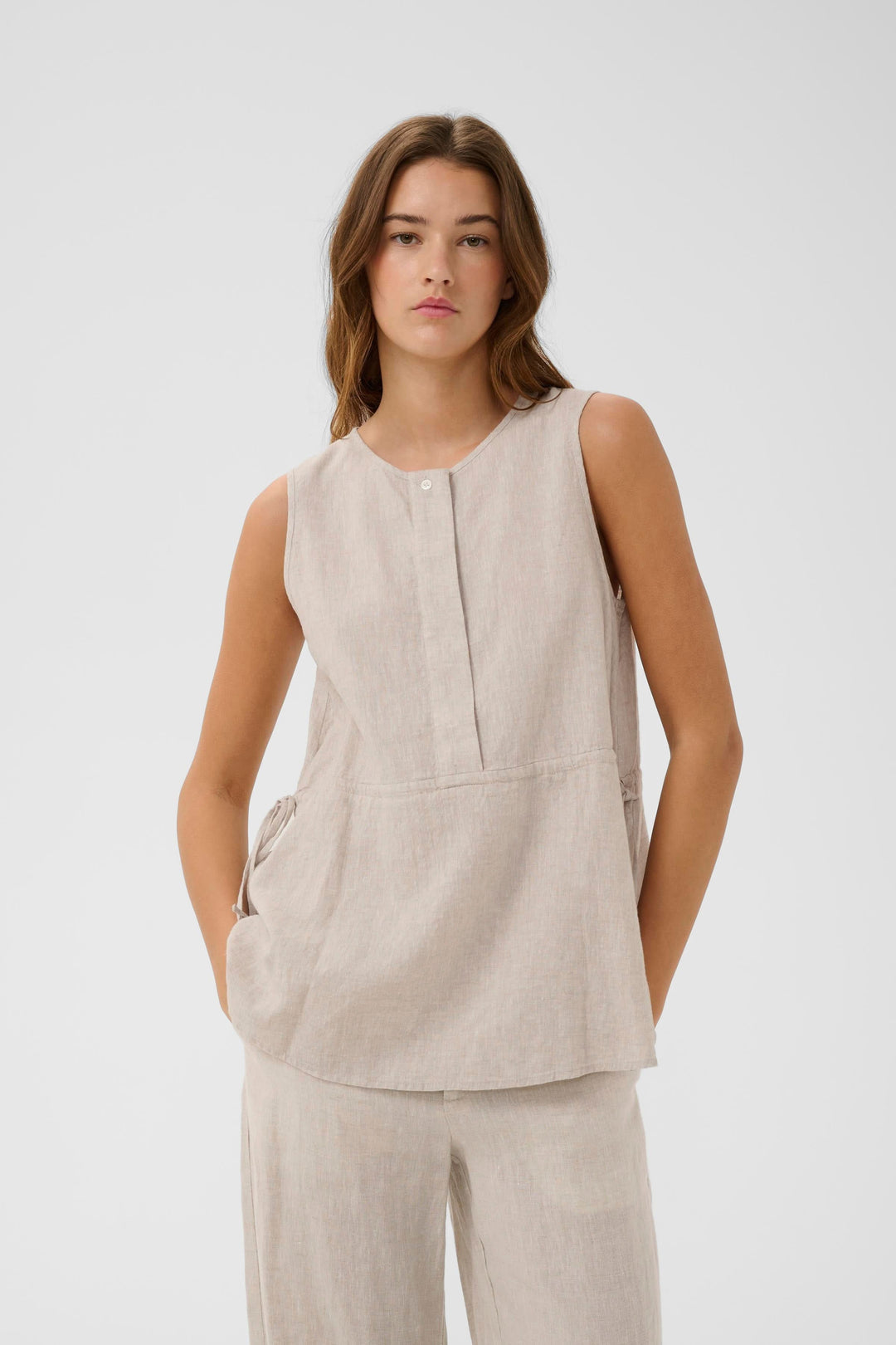 Blouse Rowan sans manches en lin portée par une femme, montrant son tissu léger et sa coupe fluide idéale pour un style minimaliste.