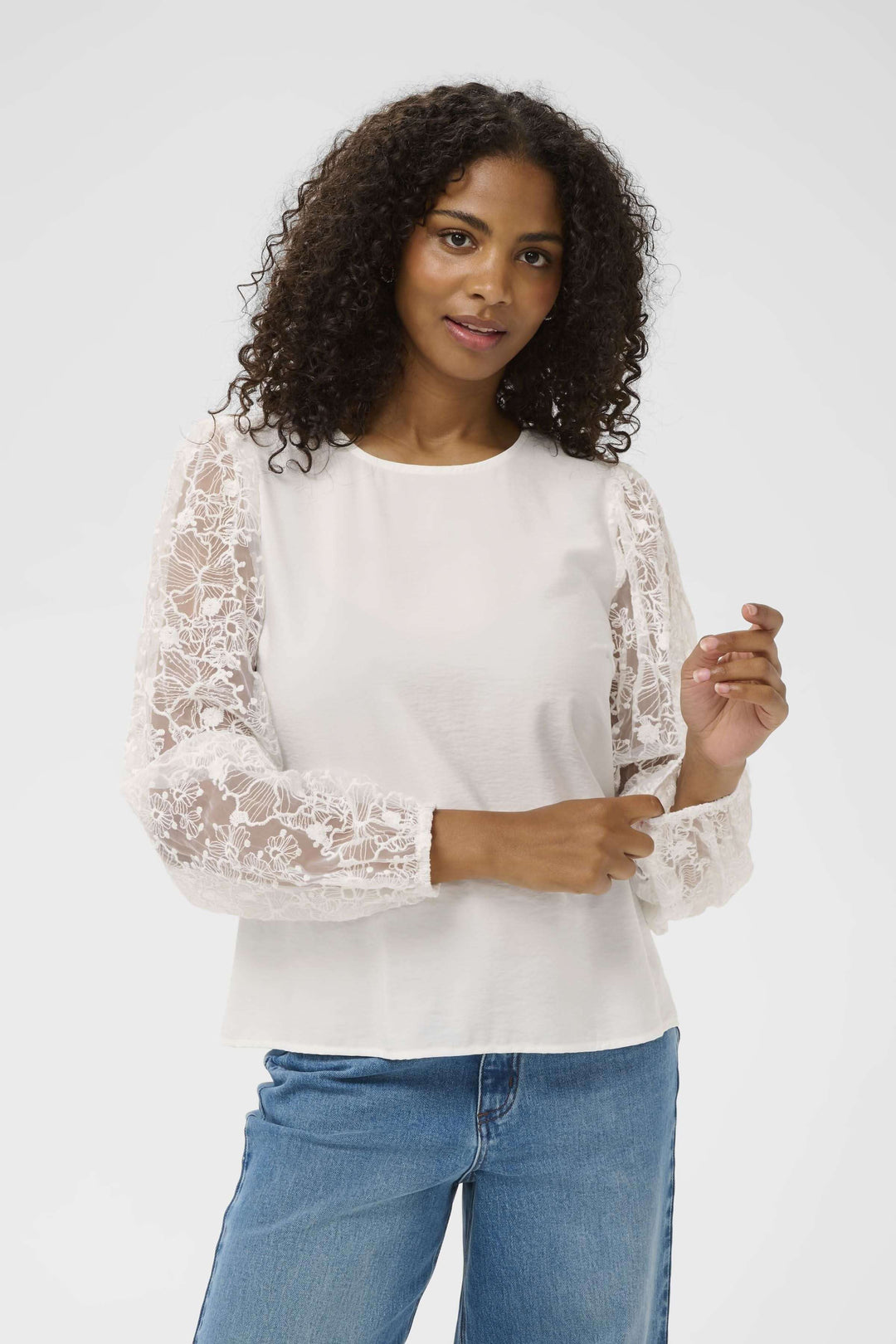 Blouse avec broderie avec manches longues en dentelle, élégante silhouette féminine pour un style raffiné, portée avec denim.