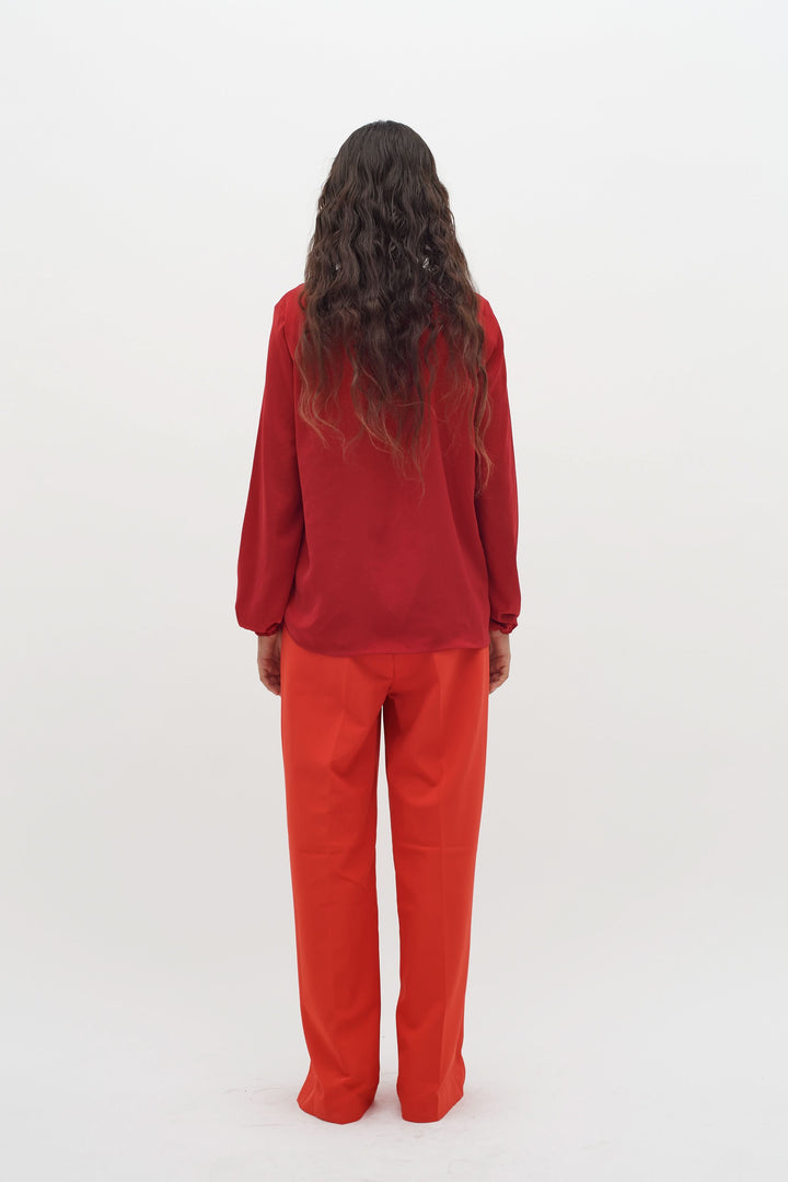 Blouse col en V rouge portée avec un pantalon orange, vue arrière, style moderne et élégant.