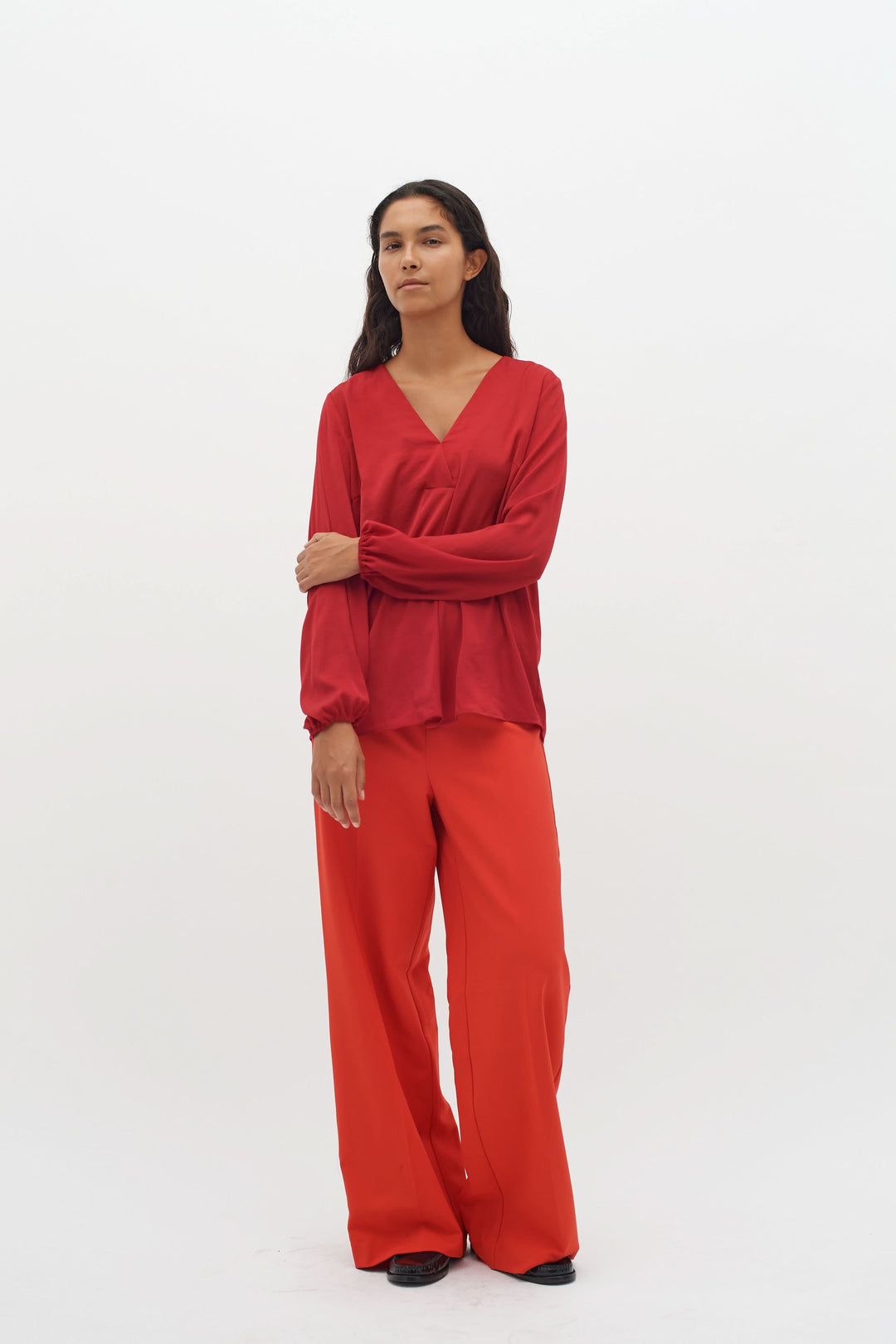 Blouse col en V Rinda rouge avec manches longues et pantalon assorti, style élégant et moderne.