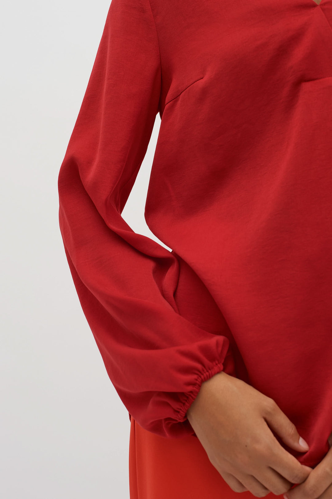 Blouse col en V Rinda rouge avec manches longues et poignets ajustés pour un look élégant.