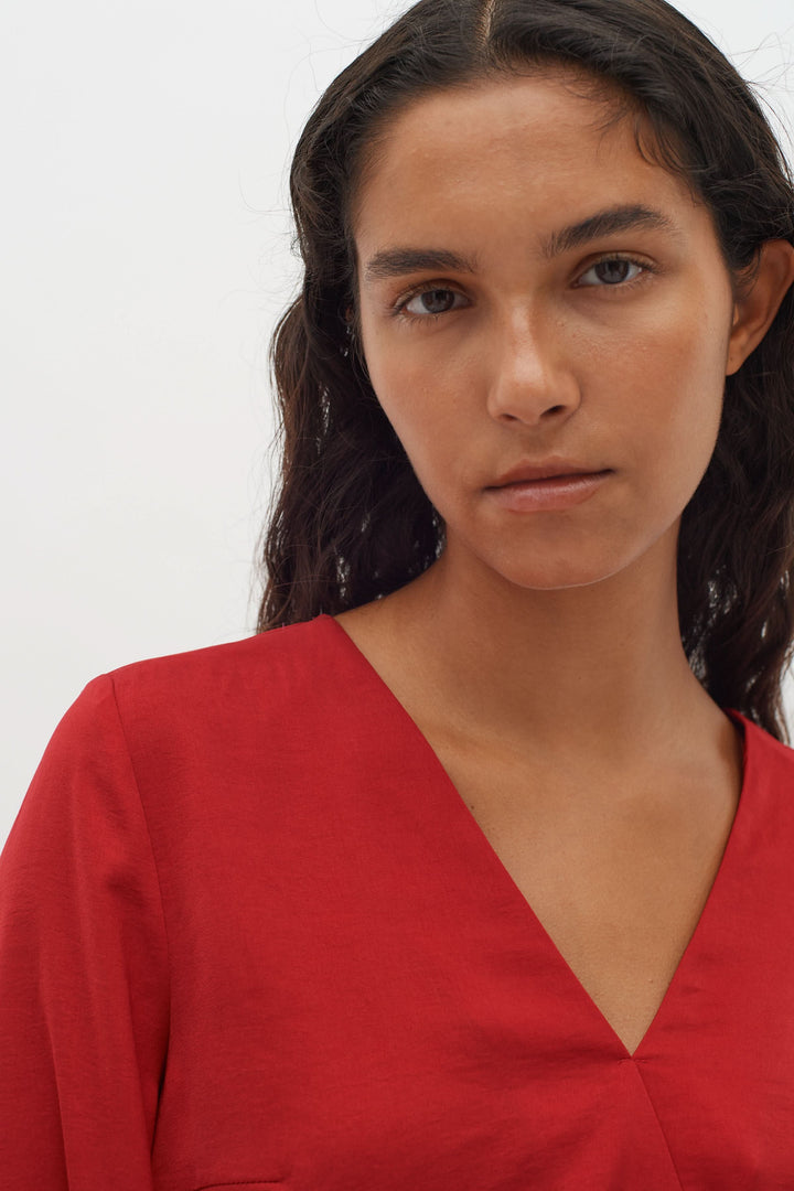 Blouse col en V Rinda en rouge, avec coupe ample et manches longues, pour un look élégant et moderne.