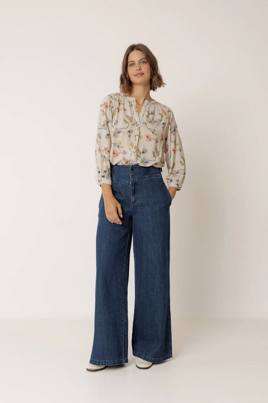 Femme portant une blouse florale à manches longues avec un imprimé délicat et un jean, offrant une silhouette élégante et fluide.