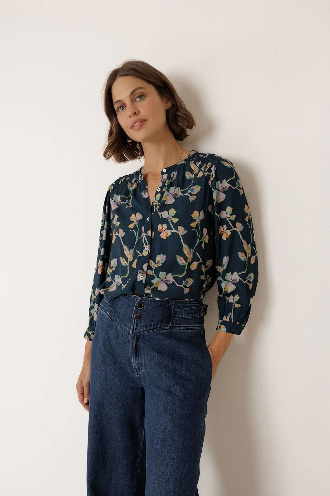 Blouse florale à manches longues en tissu léger avec imprimé floral délicat et encolure boutonnée, portée par un mannequin. Mode élégante.