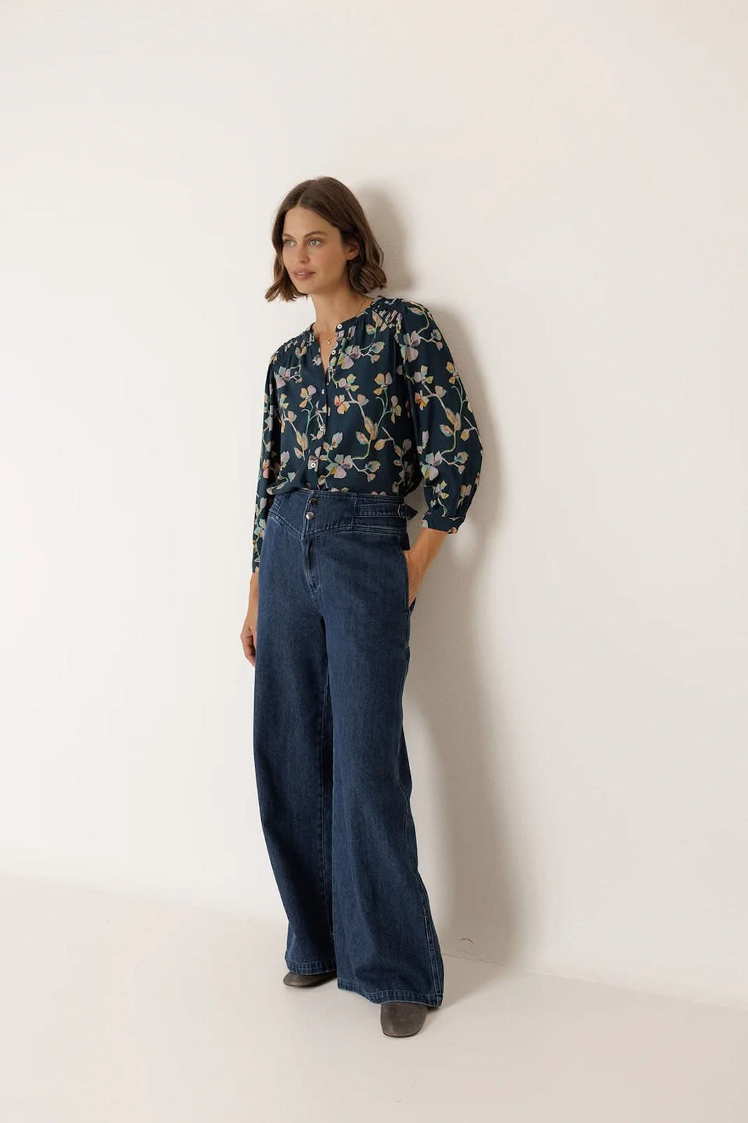 Blouse florale à manches longues au design fluide et féminin, portée avec un jean, offrant confort et élégance au quotidien.
