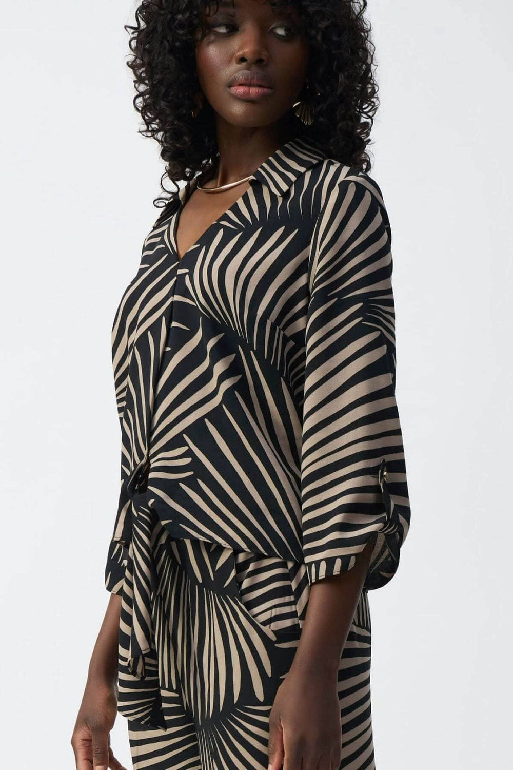 Blouse légère imprimé feuillage avec col en V, manches 3/4 et ourlet noué, style décontracté et féminin.