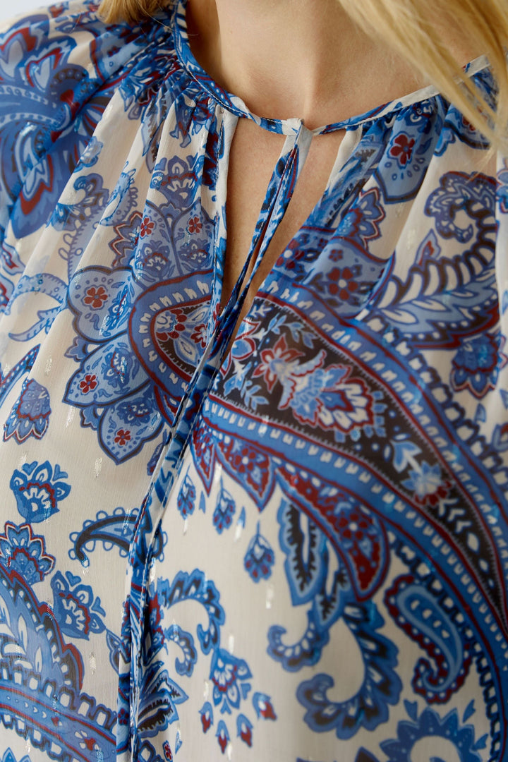 Blouse imprimée à manches longues, motif cachemire bohème, encolure fendue, matière légère et transparente, détaillée en bleu et blanc.