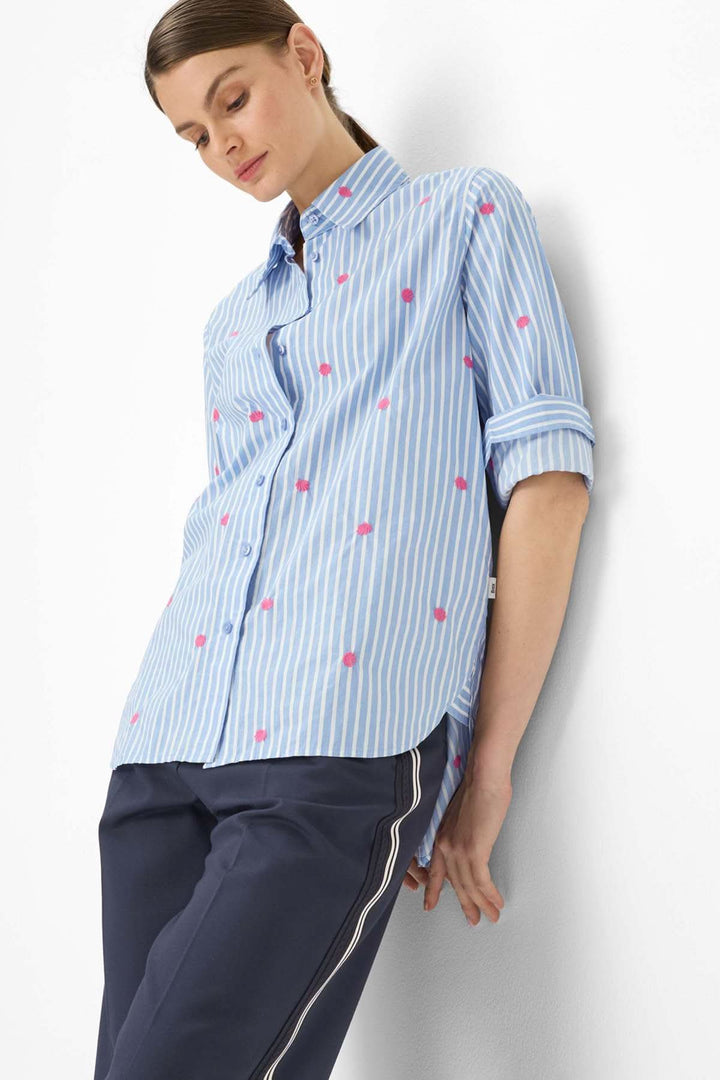Femme portant une Blouse rayée à broderies contrastantes VIKI, coupe ample, rayures verticales et broderies contrastantes.
