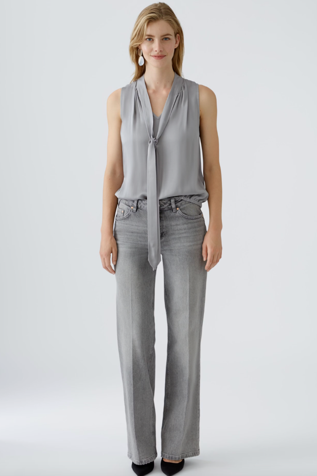 Blouse en satin brillant grise avec effet cravate, portée avec jeans gris, style décontracté, encolure en V.