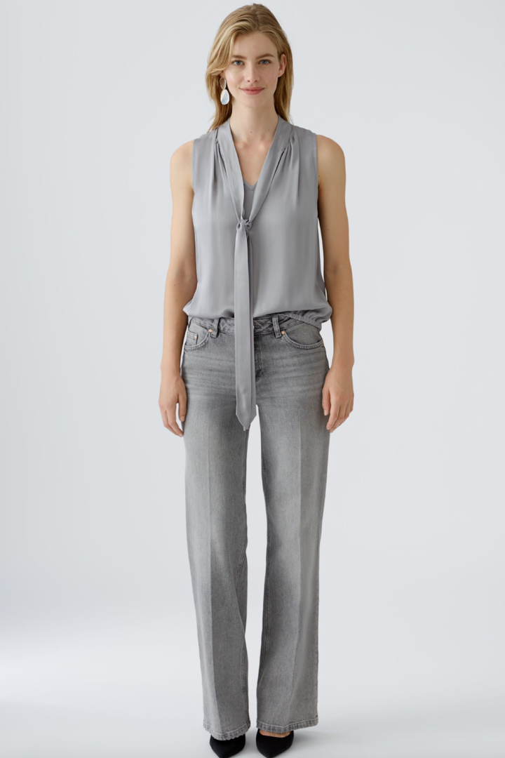 Blouse en satin brillant grise avec effet cravate, portée avec jeans gris, style décontracté, encolure en V.