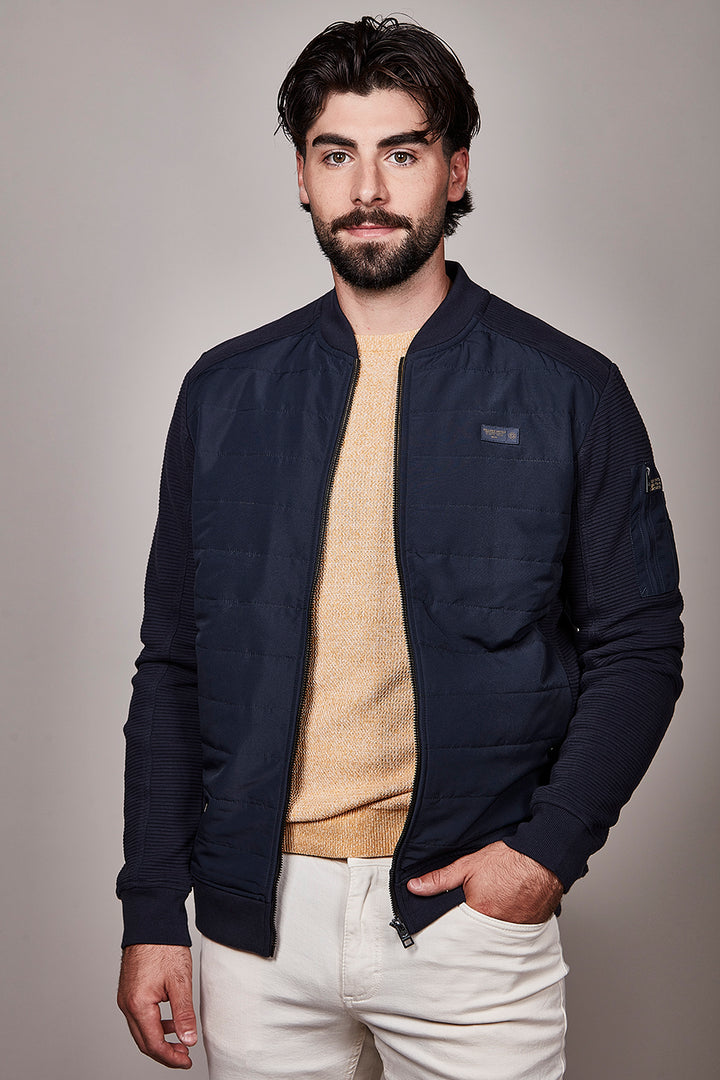 Homme portant un blouson matelassé à fermeture zippée, élégant et moderne, parfait pour la mi-saison.