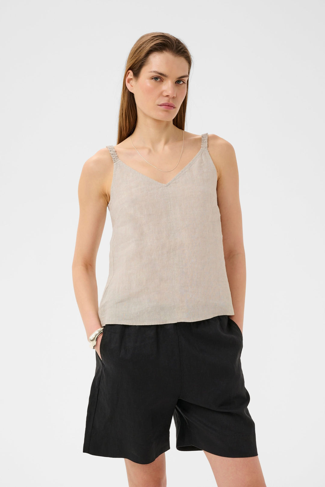 Femme portant la Camisole Elinor fluide à bretelles fines en lin avec encolure en V et coupe droite, idéale pour un look léger et élégant.