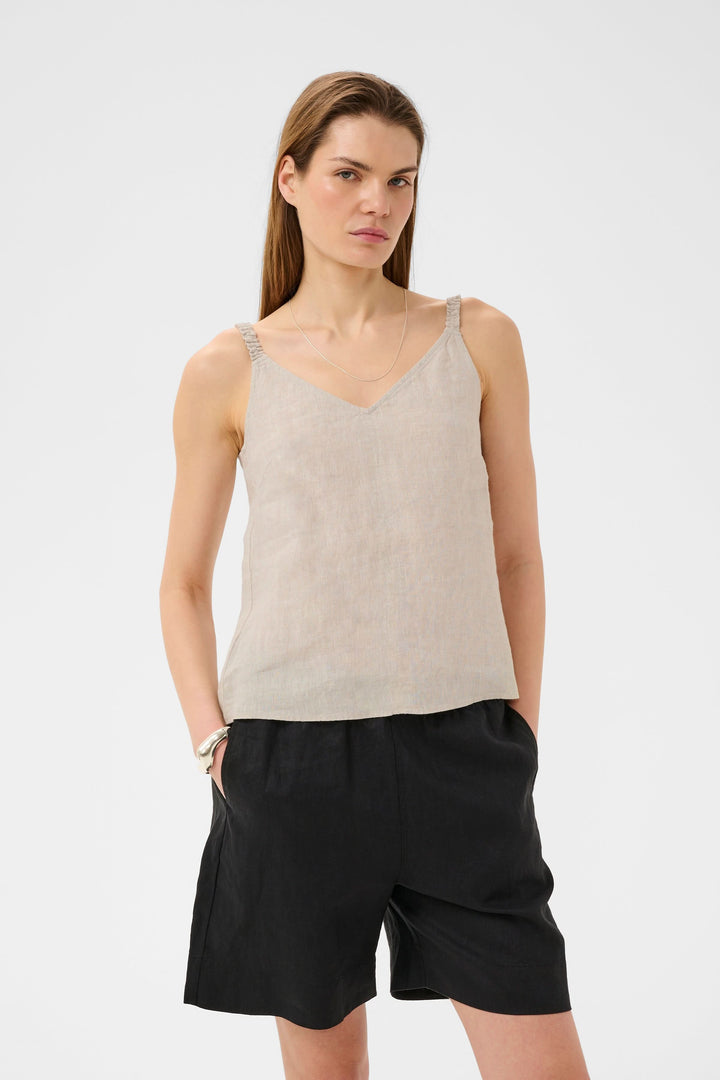 Femme portant la Camisole Elinor fluide à bretelles fines en lin avec encolure en V et coupe droite, idéale pour un look léger et élégant.