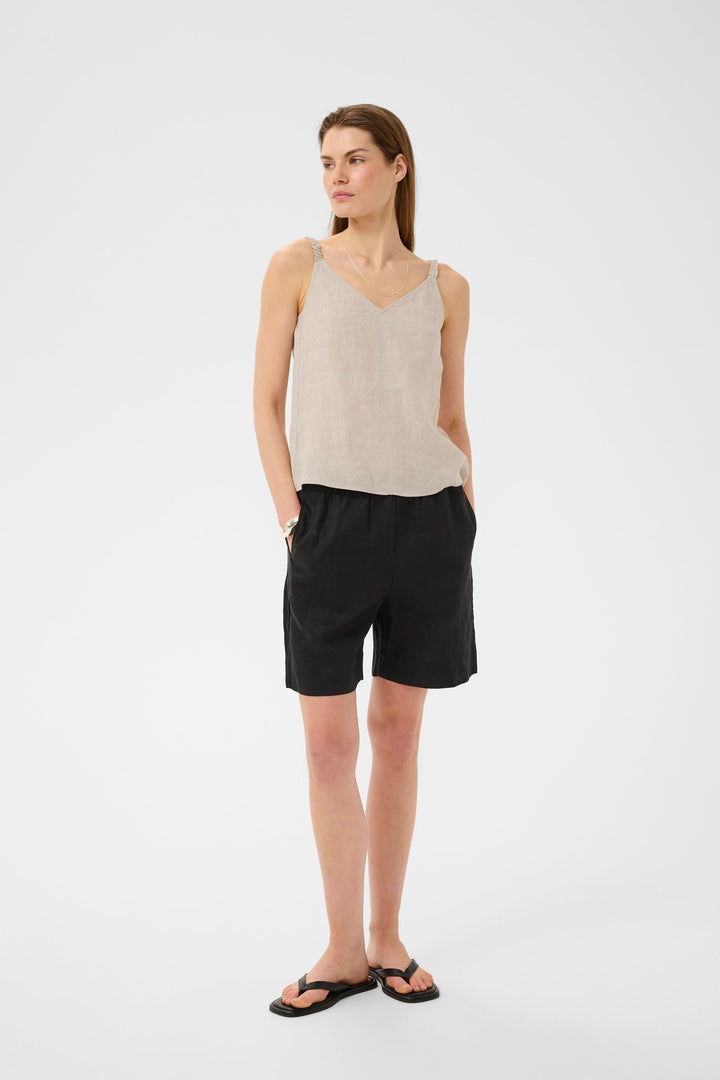 Camisole Elinor fluide à bretelles fines en lin avec encolure en V, présentée sur une femme, parfaite pour un look estival élégant.