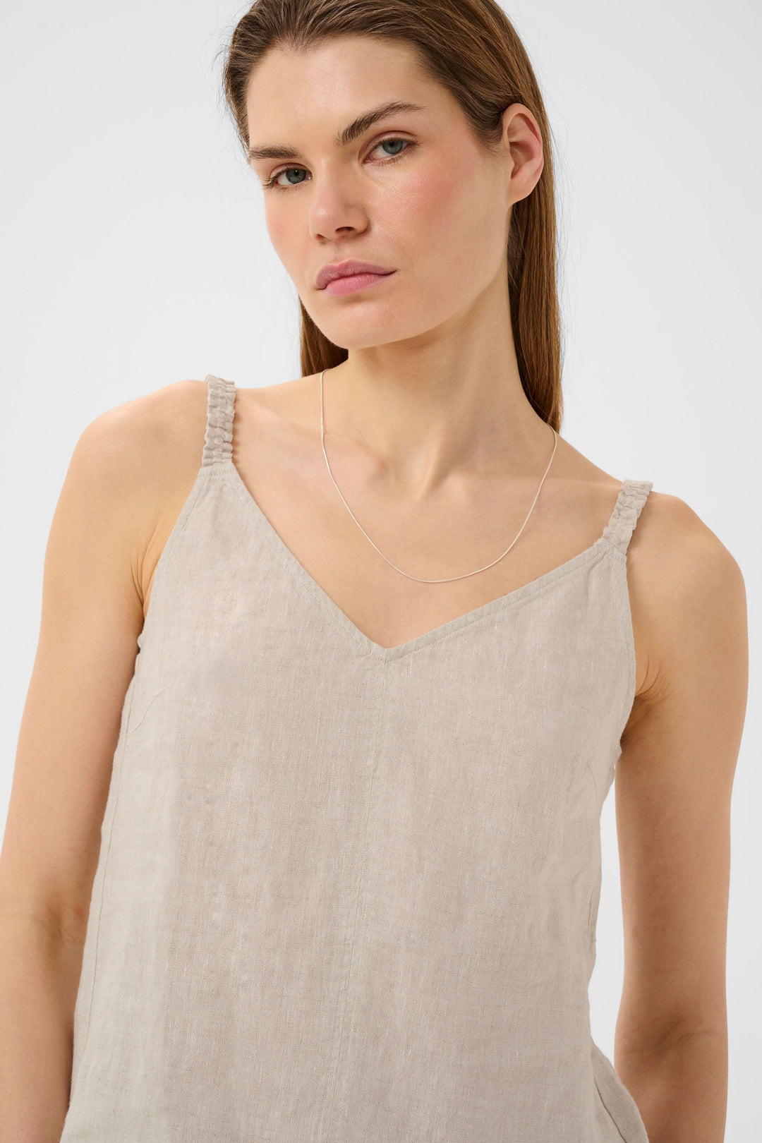Femme portant la Camisole Elinor fluide à bretelles fines, encolure en V et tissu léger en lin, finition élégante et confortable.