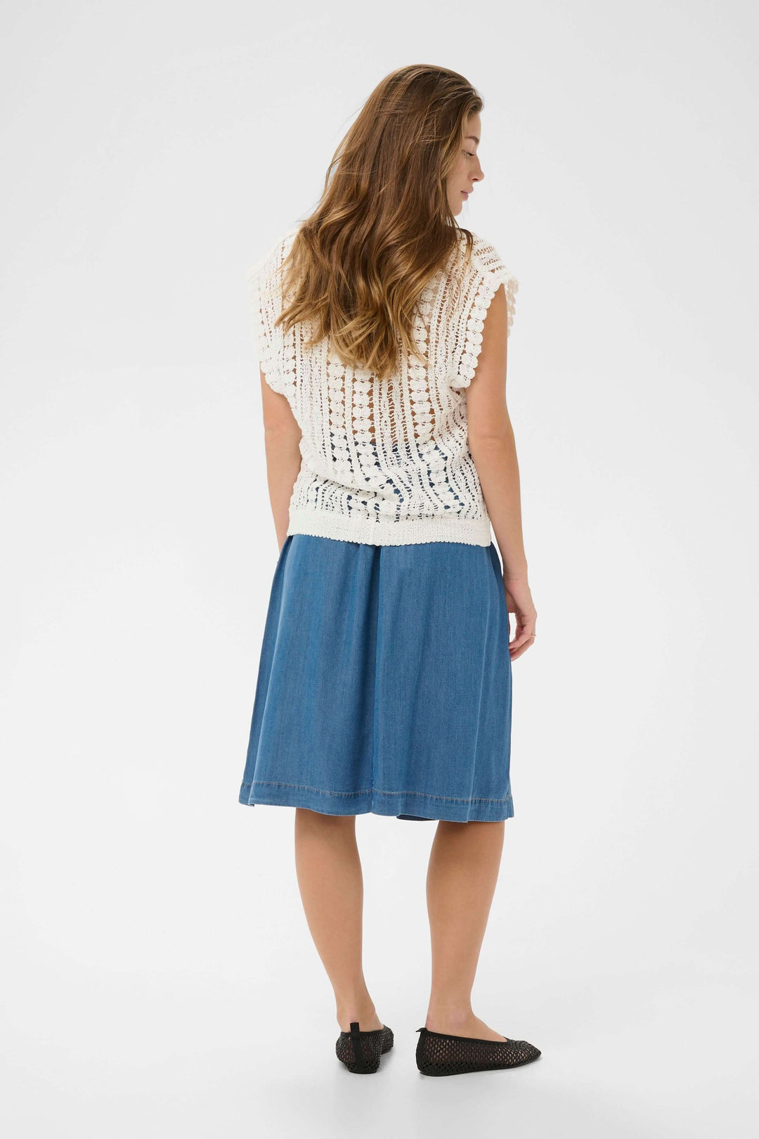 Femme portant une Camisole Tilda en maille ajourée blanche avec jupe en jean, vue arrière.