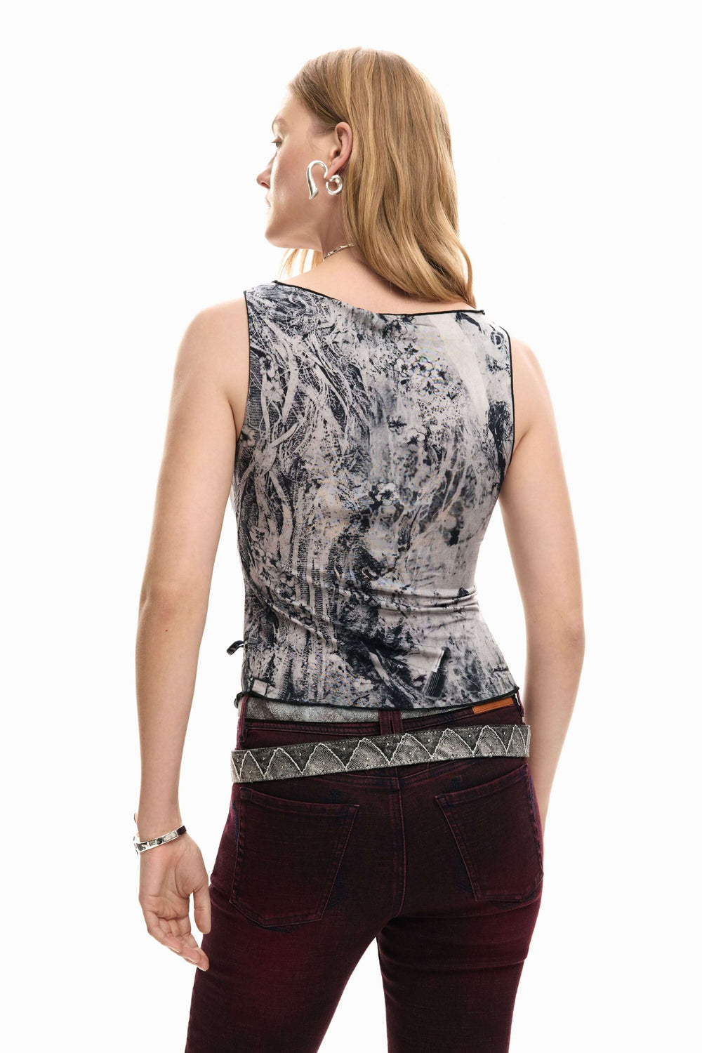 Dos d'une femme portant une camisole ajustée à imprimé artistique avec un laçage latéral décoratif.