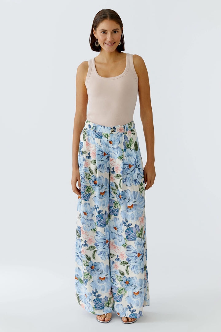 Femme portant une camisole côtelée essentielle beige avec pantalon fleuri, parfait pour un look estival décontracté.