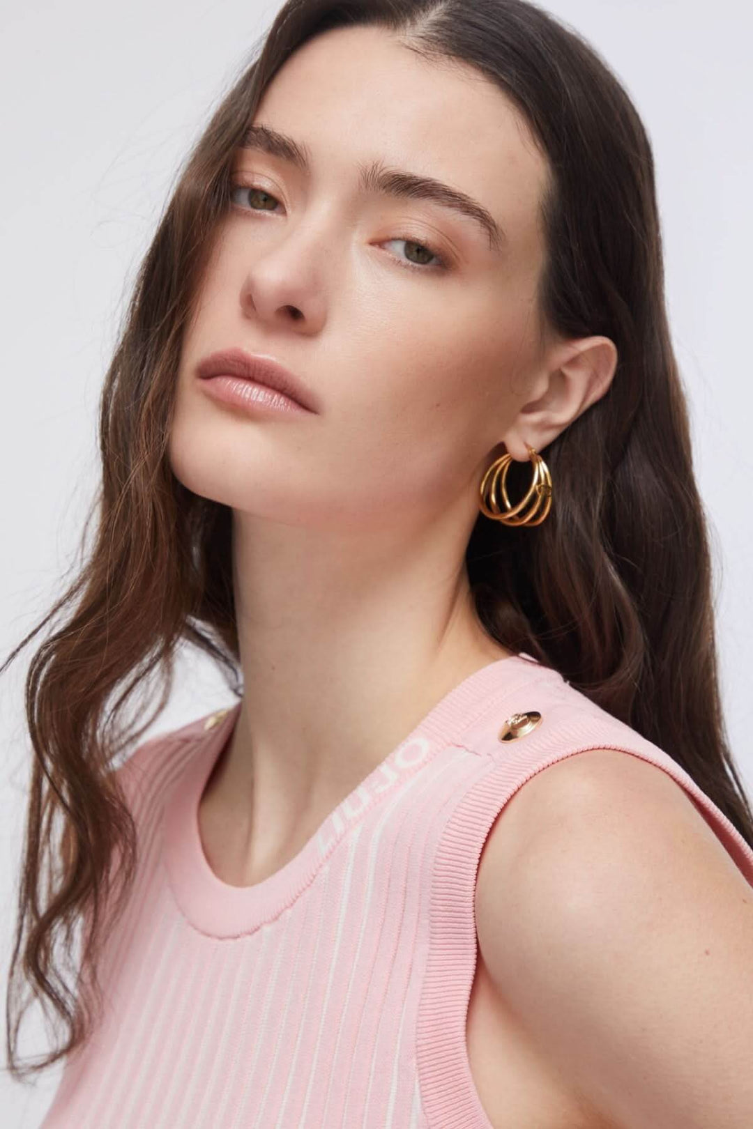 Femme portant une camisole en maille côtelée rose avec encolure ronde et sans manches, coiffée de boucles d&