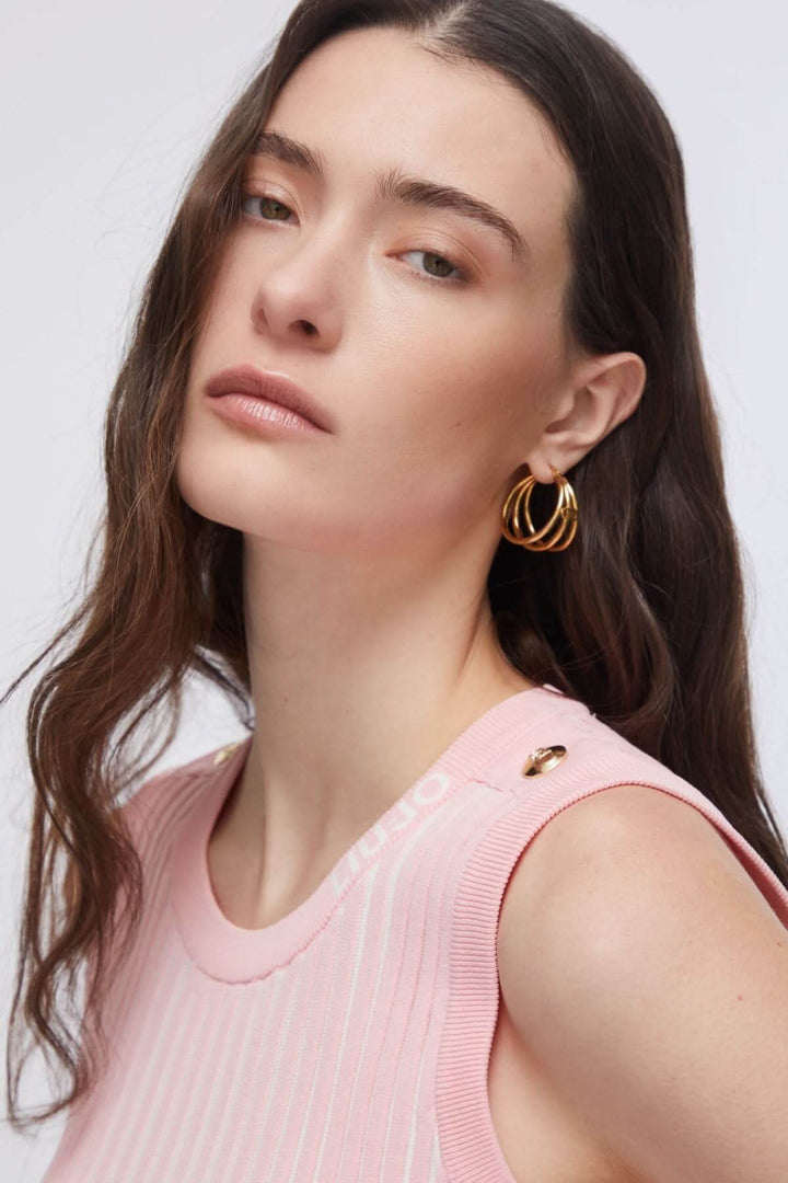 Femme portant une camisole en maille côtelée rose avec encolure ronde et sans manches, coiffée de boucles d&