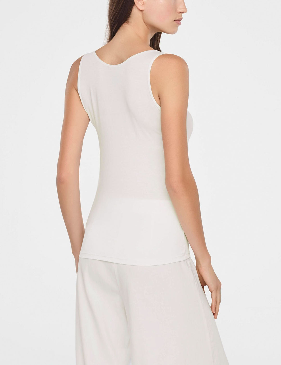 Femme portant une camisole essentielle ajustée sans manches, coupe ajustée, encolure arrondie et matière douce.