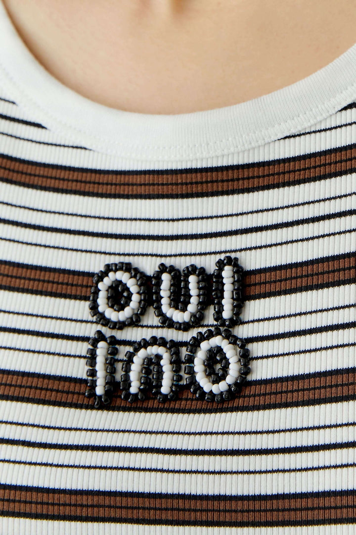 Camisole à rayures avec détail brodé "oui non" sur un fond côtelé blanc et marron, idéale pour un look estival moderne.