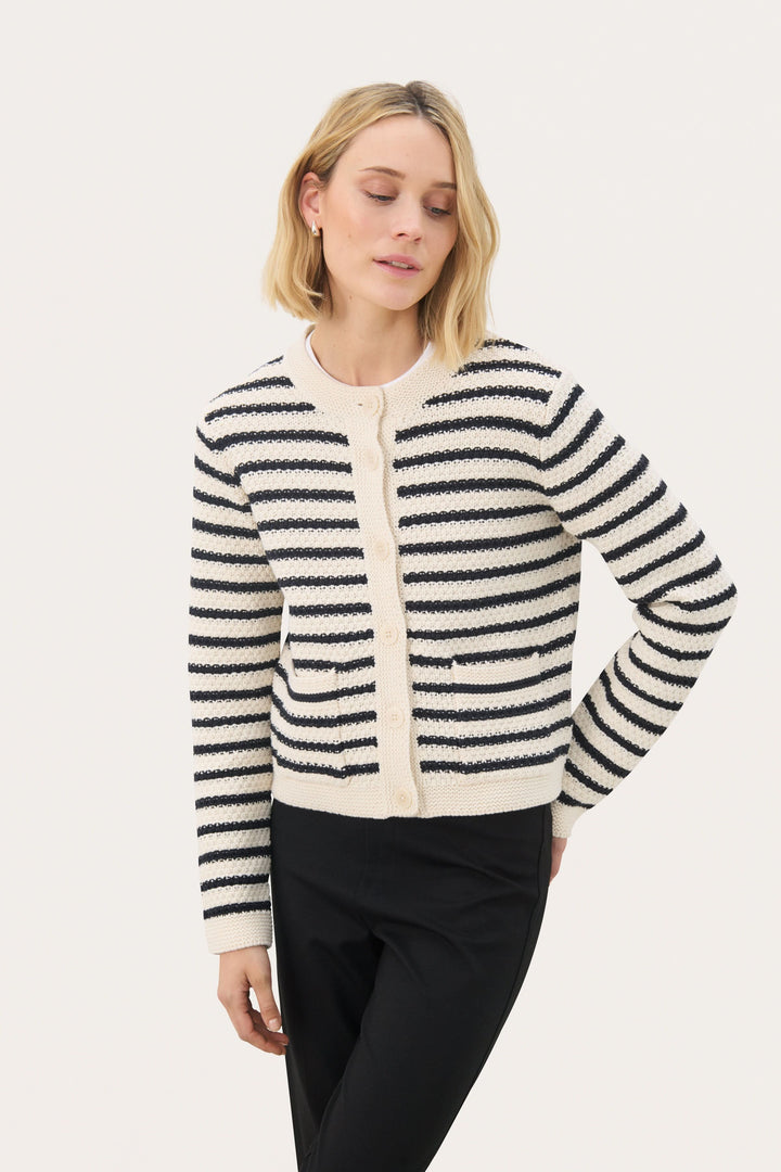 Femme portant le cardigan Elmie à rayures texturées et coupe droite, coordonné avec un pantalon noir pour un style chic et décontracté.