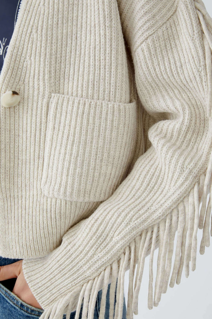 Cardigan beige avec franges, poches plaquées, décolleté en V et tricoté en mélange coton et laine.