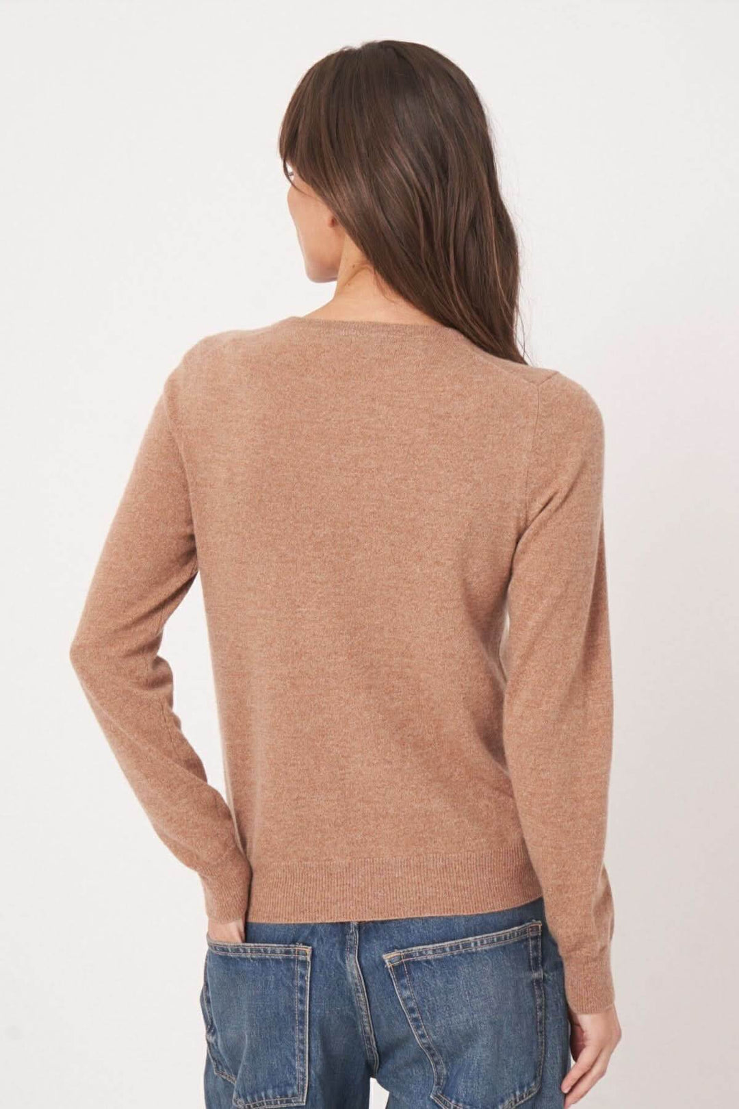 Cardigan classique beige avec coupe ajustée et encolure ronde, vu de dos, porté avec un jean.