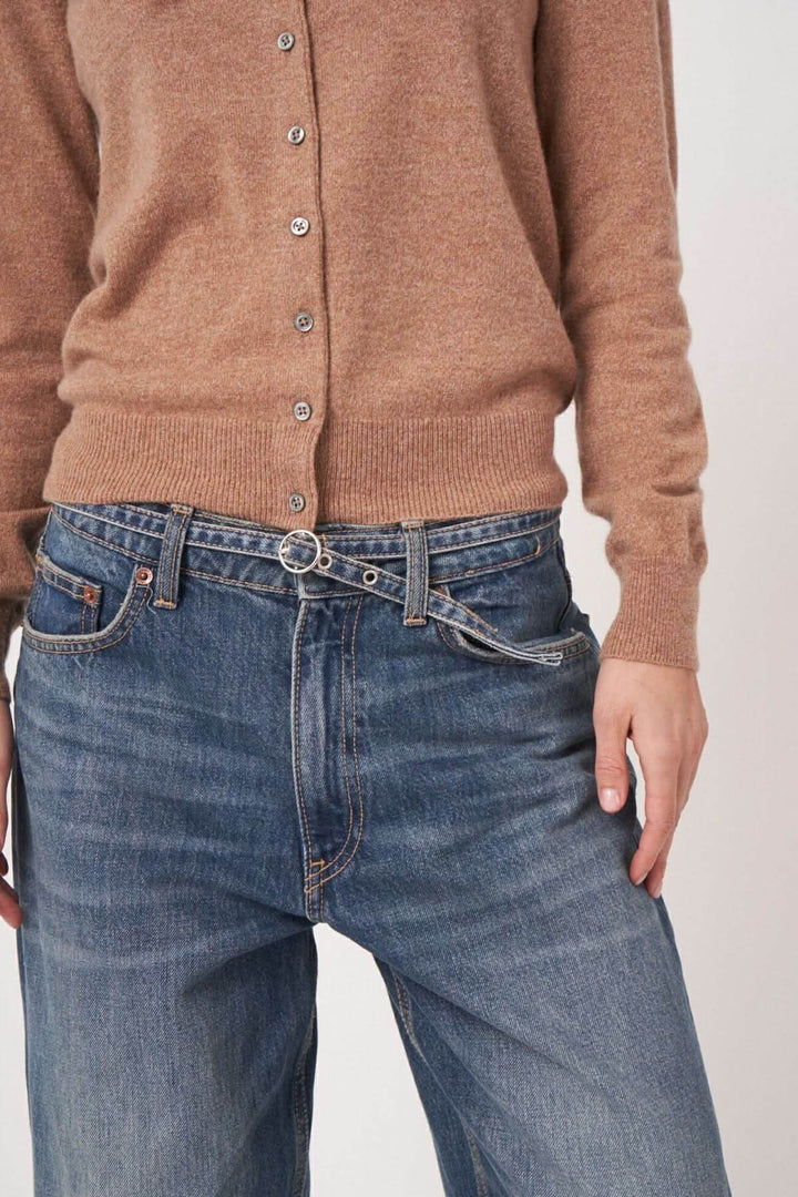 Cardigan classique beige boutonné porté avec un jean décontracté pour un look chic et élégant.