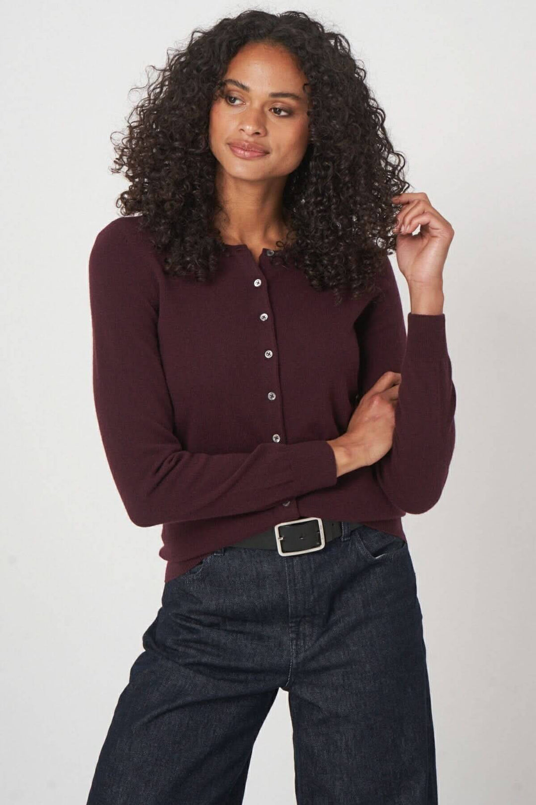 Modèle portant un cardigan classique bordeaux à boutons, associé à un pantalon en denim.
