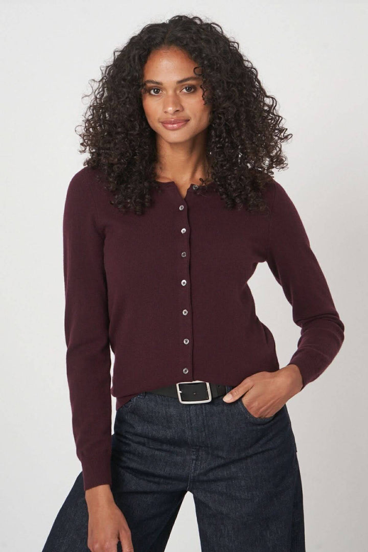 Cardigan classique boutonné en mailles douces, coupe ajustée, couleur bordeaux, porté avec un pantalon en denim.