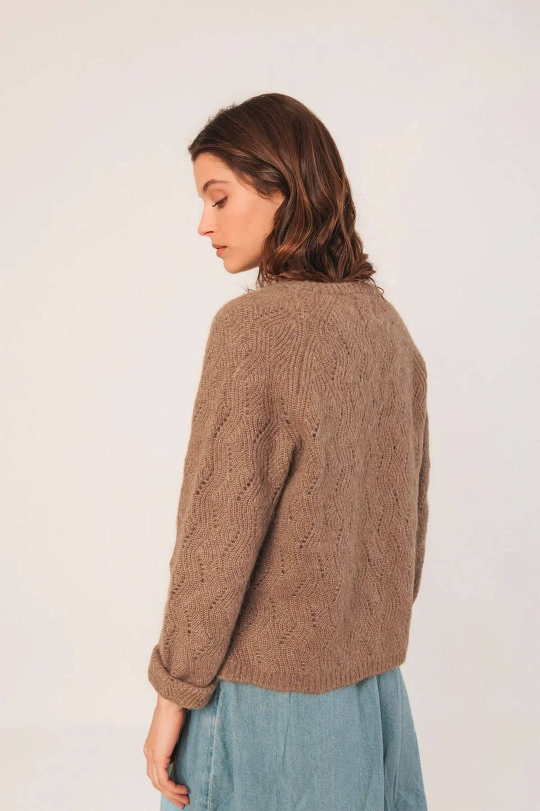 Cardigan en maille texturée brun, col rond, coupe droite, porté sur une blouse fluide, style décontracté.