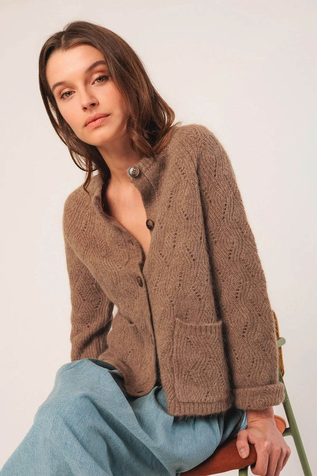 Femme portant un cardigan en maille texturée, col rond, couleur beige, coupe droite, style décontracté.