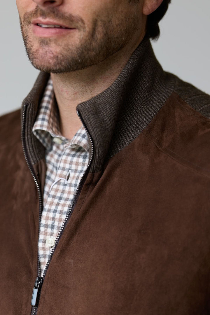 Homme portant un cardigan à empiècements en suédine avec col montant et fermeture zippée, ajoutant une touche élégante et confortable.
