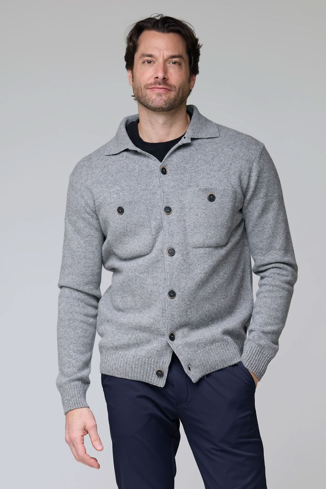 Homme portant un cardigan à poches plaquées en laine grise, avec fermeture à boutons contrastants et poignets côtelés.