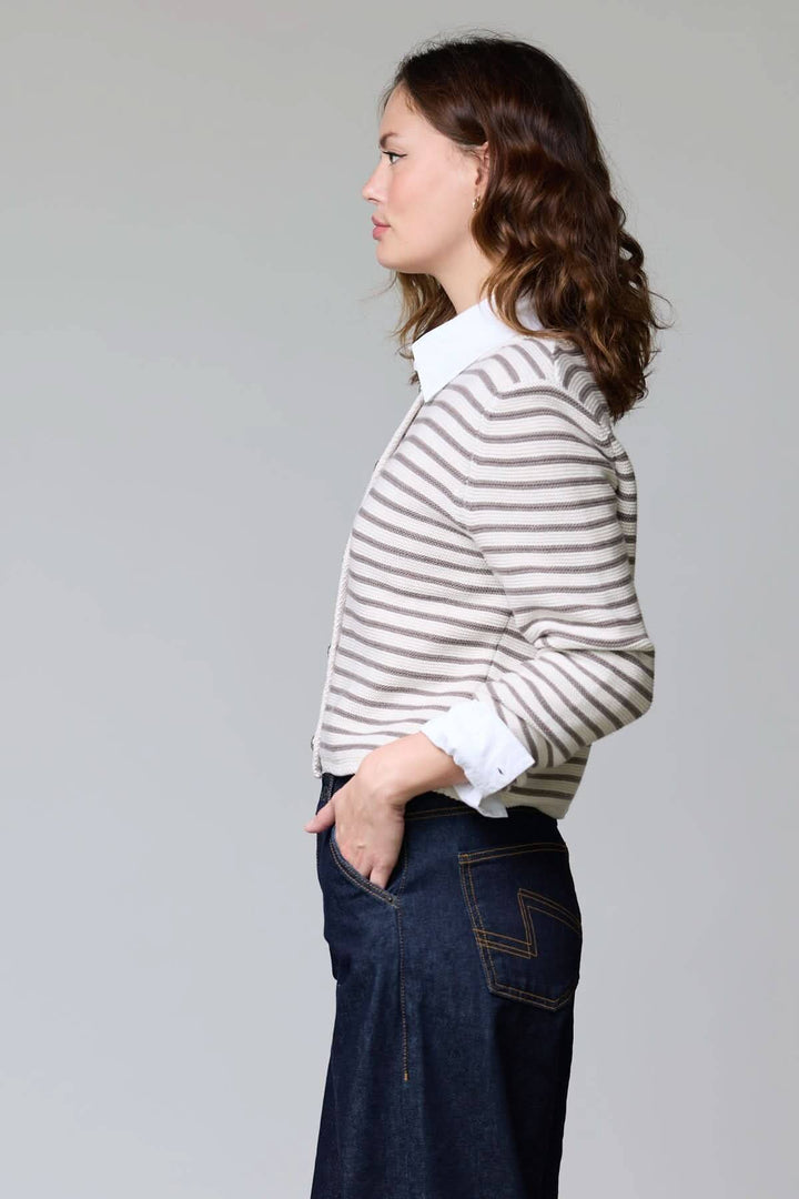Femme portant un cardigan rayé court à boutons, élégant et décontracté, parfait pour superposer sur une chemise blanche.