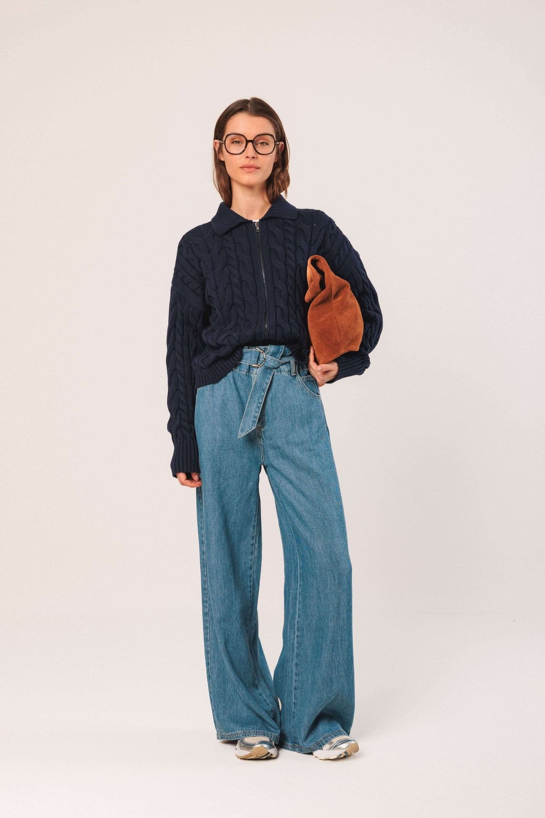 Cardigan à torsades navy, associé à un pantalon large et un sac, offrant un look moderne et décontracté.