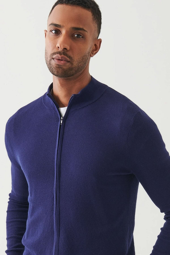 Cardigan zippé en coton et cachemire, élégant et doux, porté par un homme, coloris bleu marine.