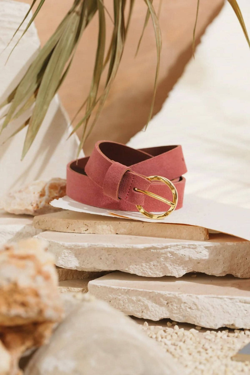 Ceinture Marais en cuir rose avec boucle martelée dorée, style bohème chic, décorée sur un fond naturel.