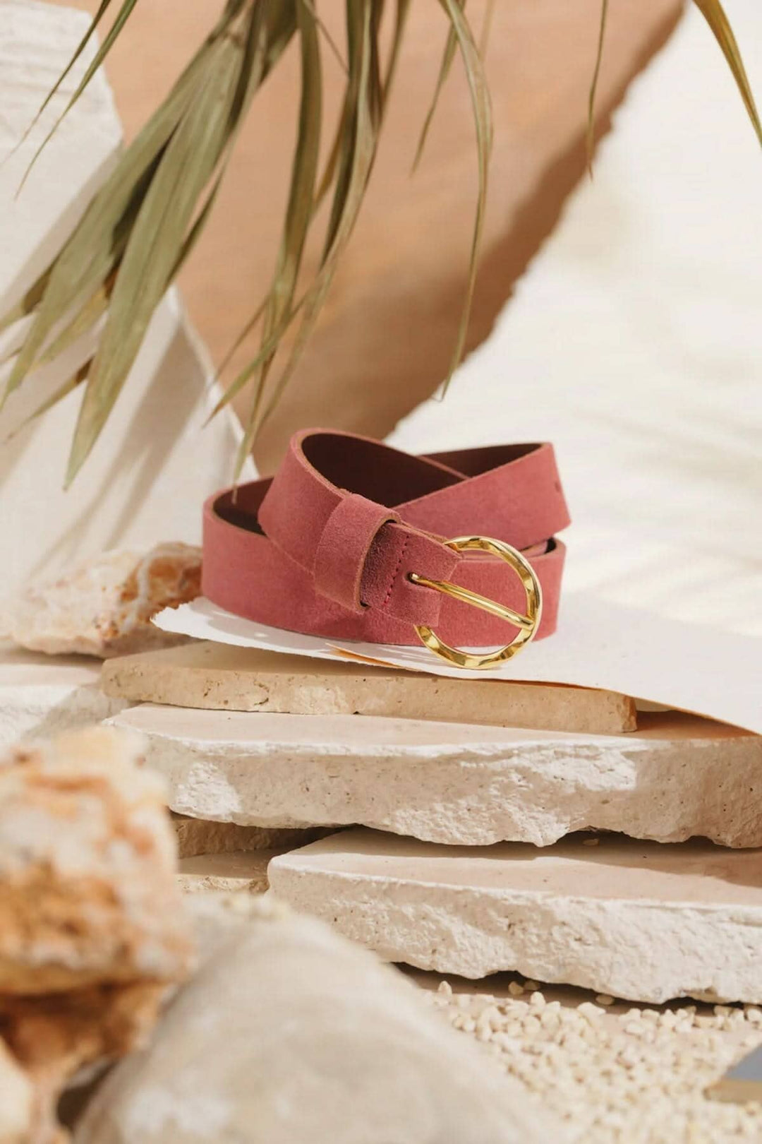 Ceinture Marais en cuir rose avec boucle martelée dorée, style bohème chic, décorée sur un fond naturel.
