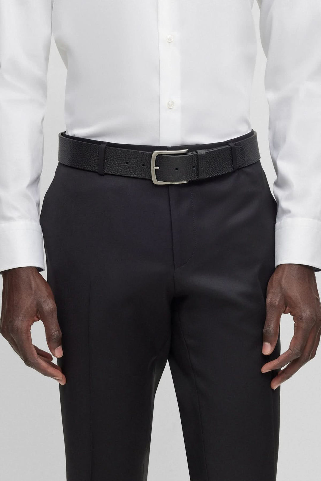 Ceinture en cuir italien à grain portée avec une chemise blanche et un pantalon noir.